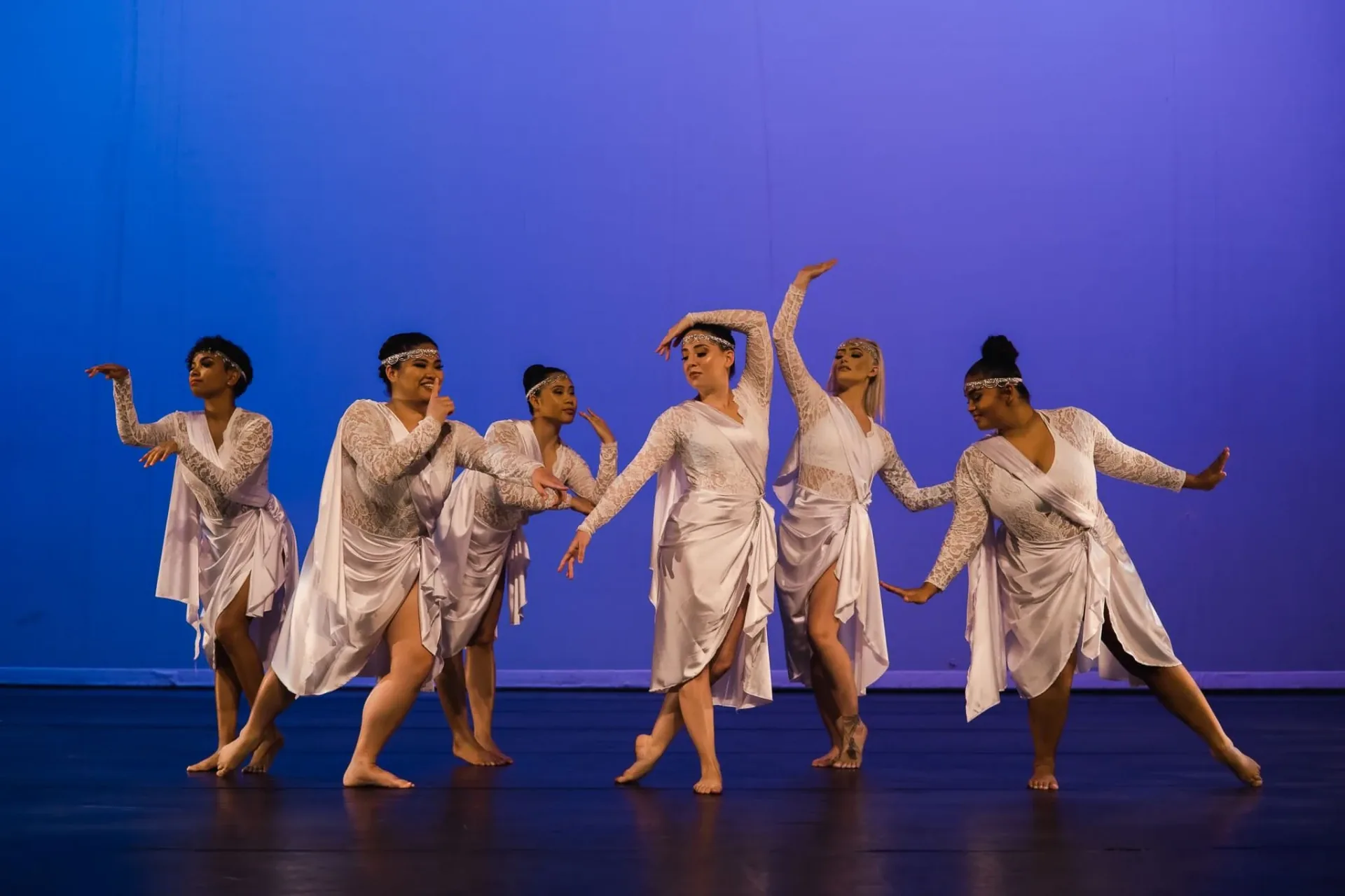 Dancers in white costumes on a blue-lit stage