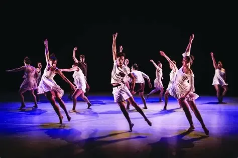 A young dance ensemble performing under stage light